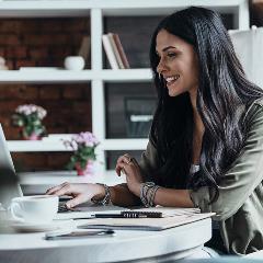 Woman smiling at desk using laptop in office setting