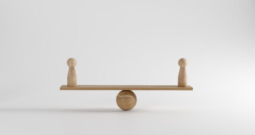 Two small wooden figures on either side of a scale, showing balance.